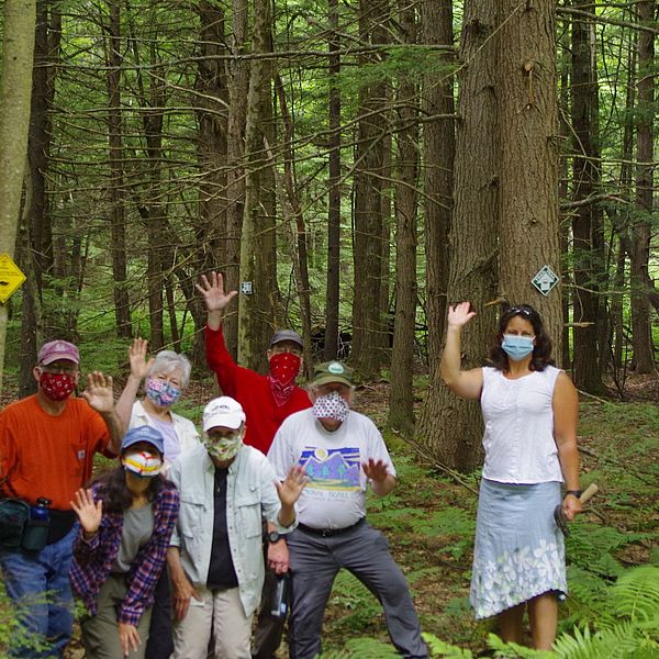A group of people waving near the entrance of the new Sunset View Farm hiking trail.